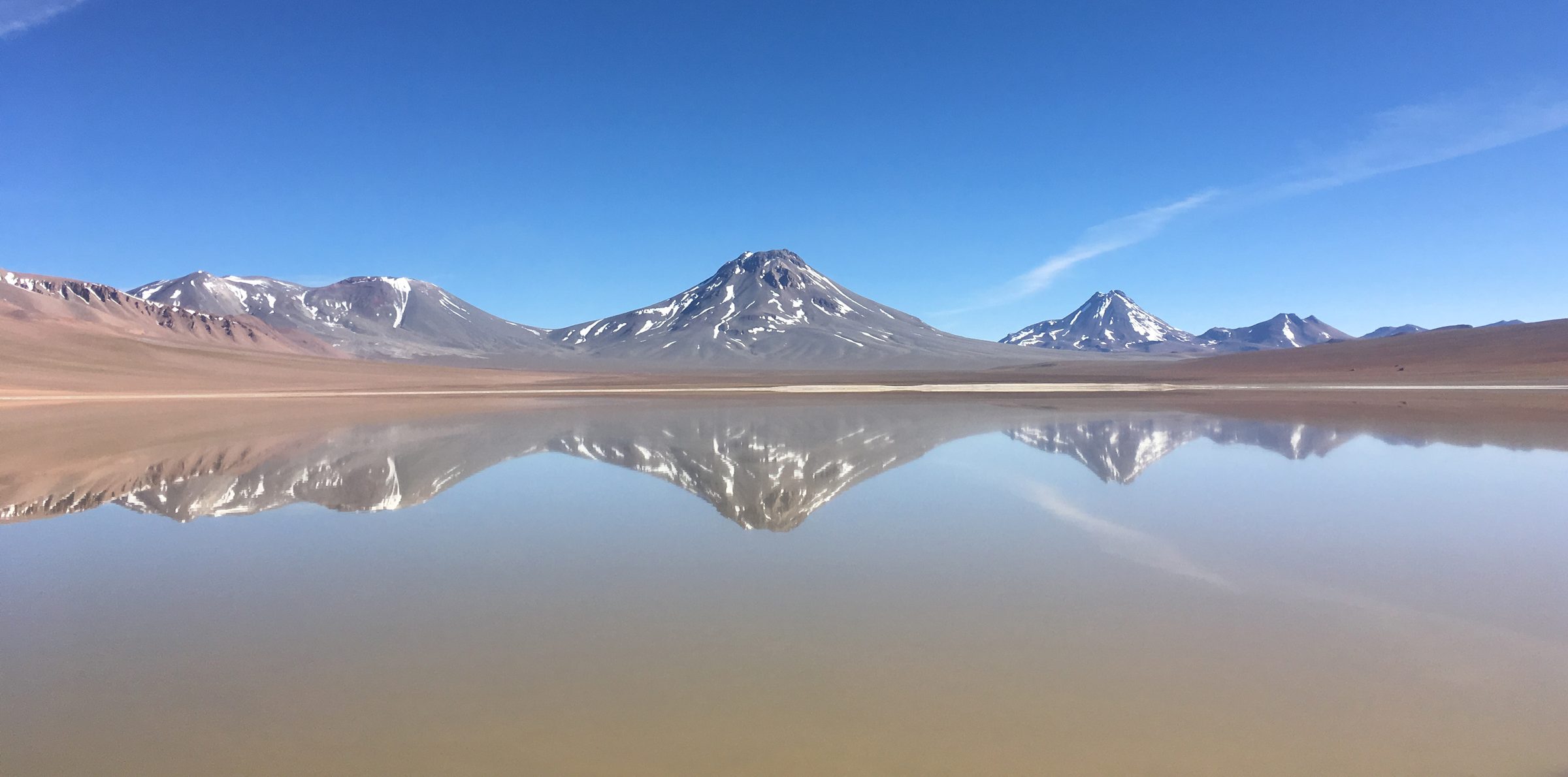 Snow-capped volcanoes reflected in Laguna Lejía, Chile