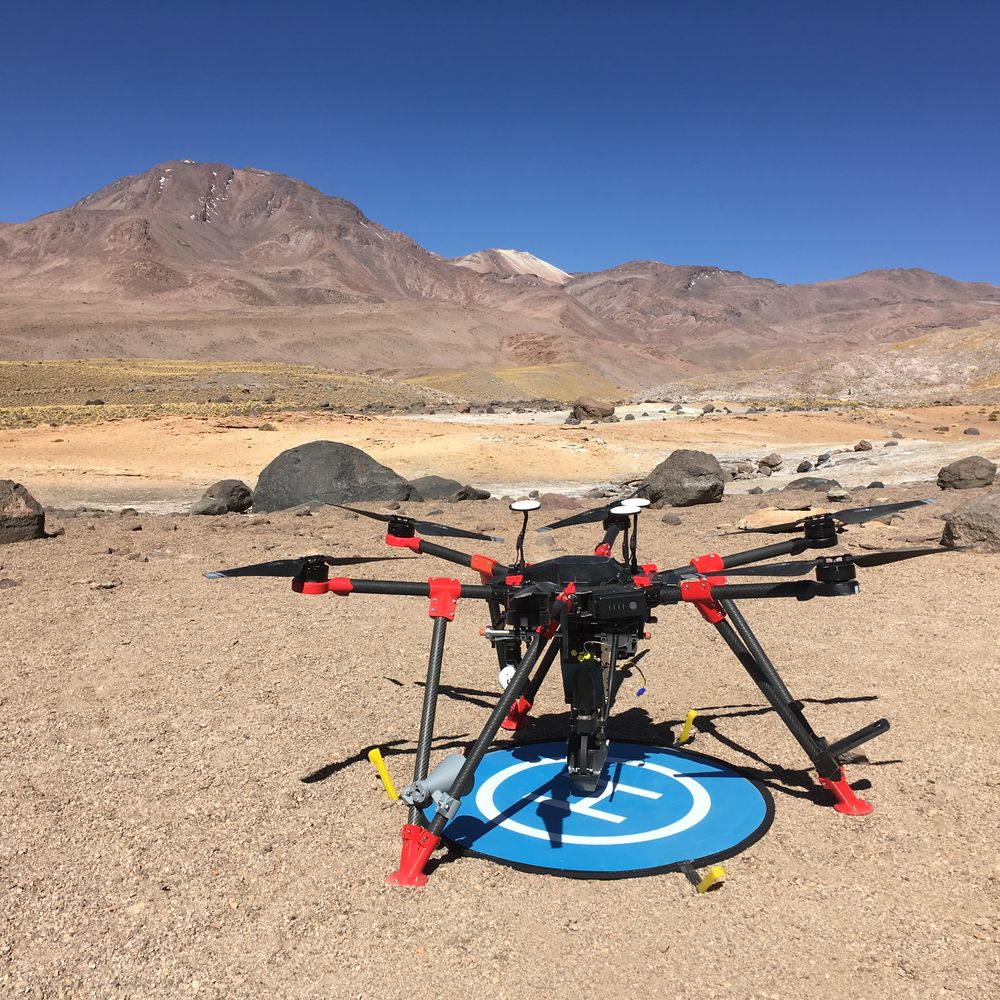 Hexacopter survey drone on a landing pad in front of a volcano