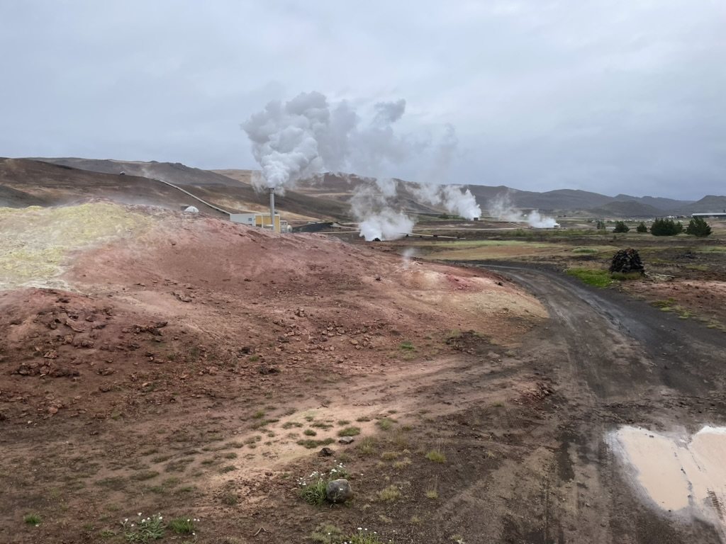 Steam rising from fumaroles across red and yellow altered ground