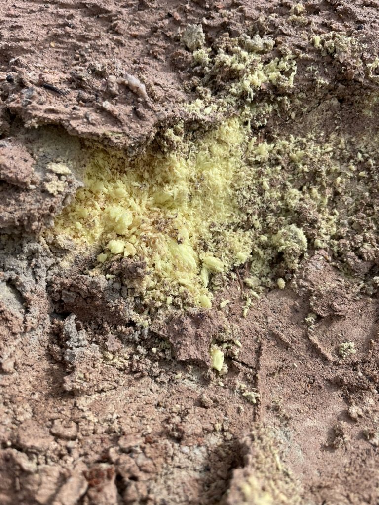 Yellow sulfur crystals on red-brown altered ground